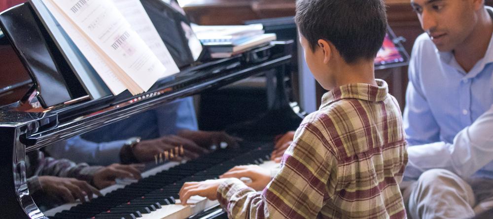 Photo of a piano student and their teacher