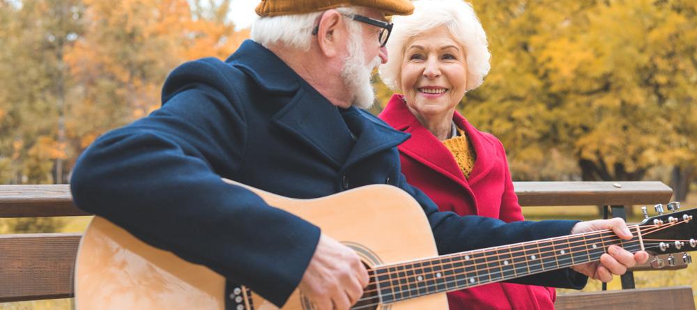 Photo of a senior couple with the gentleman playing an acoustic guitar