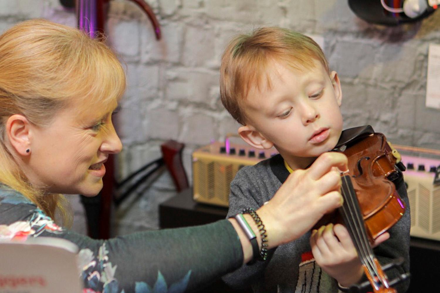 Photo of a violin teacher teaching a young boy