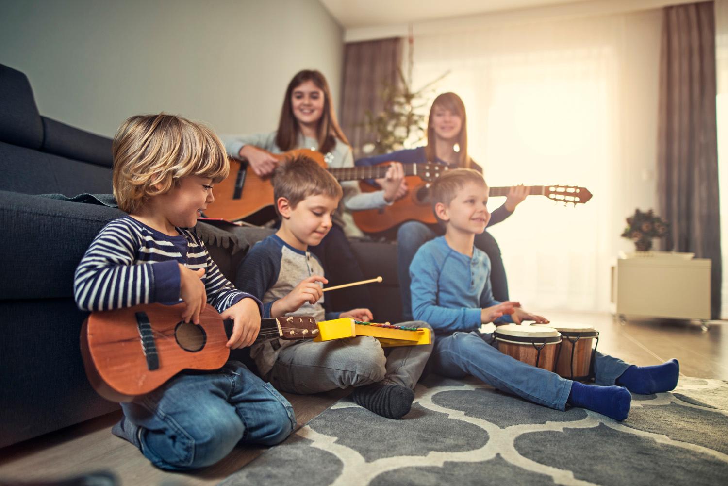 Photo of young playing musical instruments in front of the Christmas tree