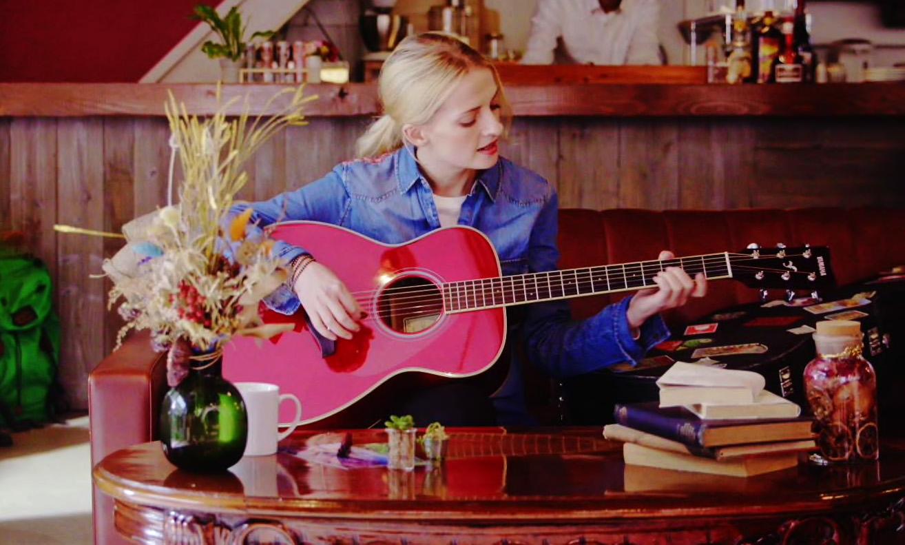 A woman playing a TransAcoustic guitar in a coffee shop